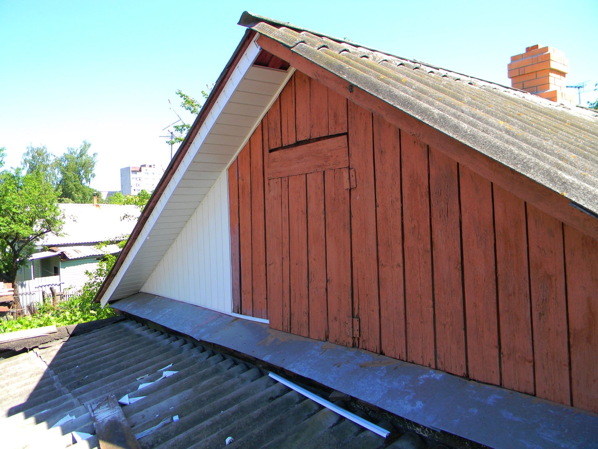 Old house with asbestos roof renovation with plastic siding installation.